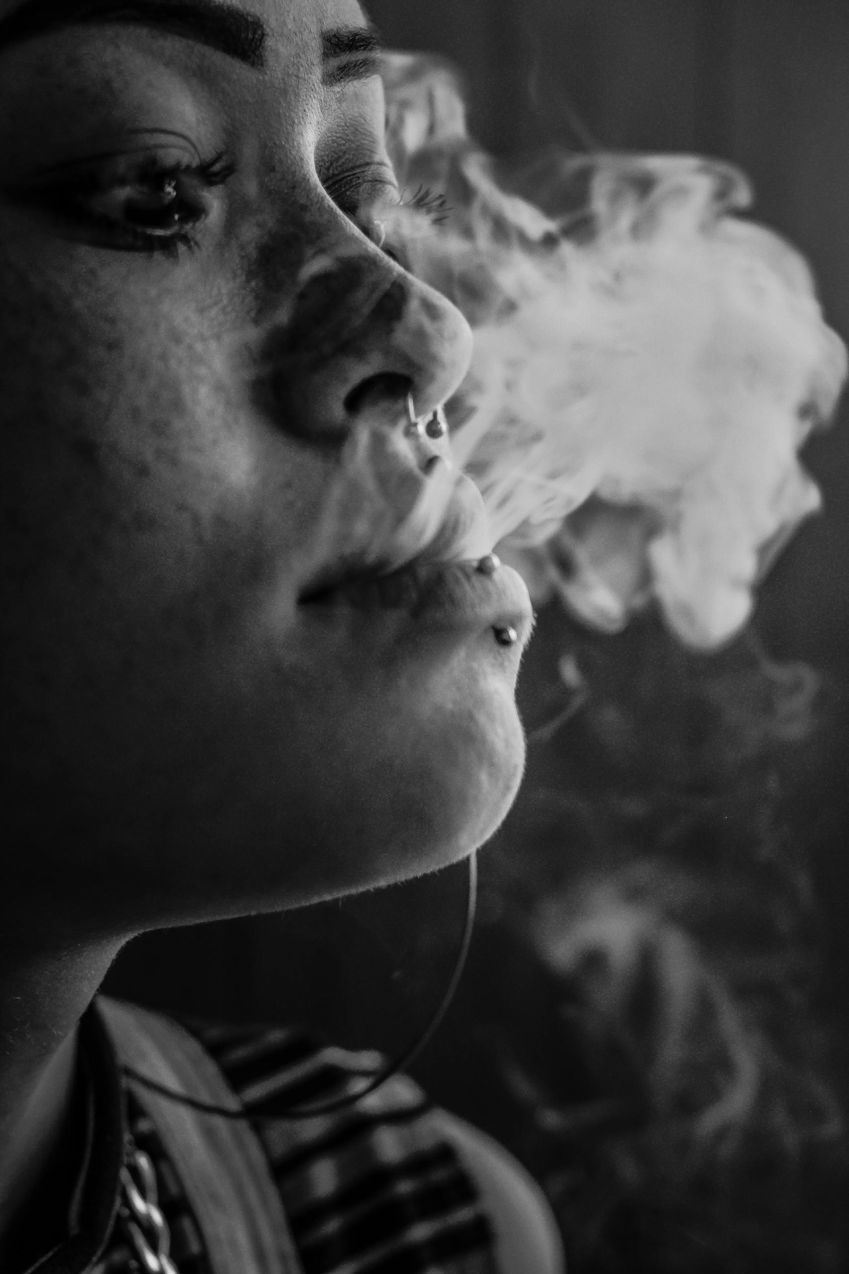 Artistic monochrome portrait capturing smoke curling from a woman's lips.